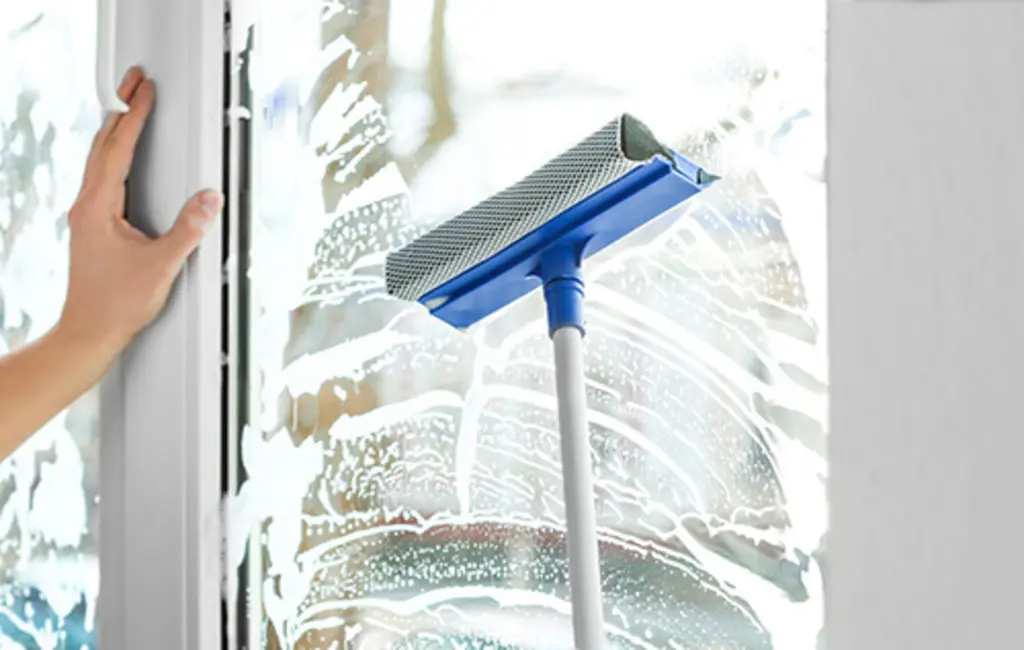 Cleaner polishing exterior windows of a Tauranga house